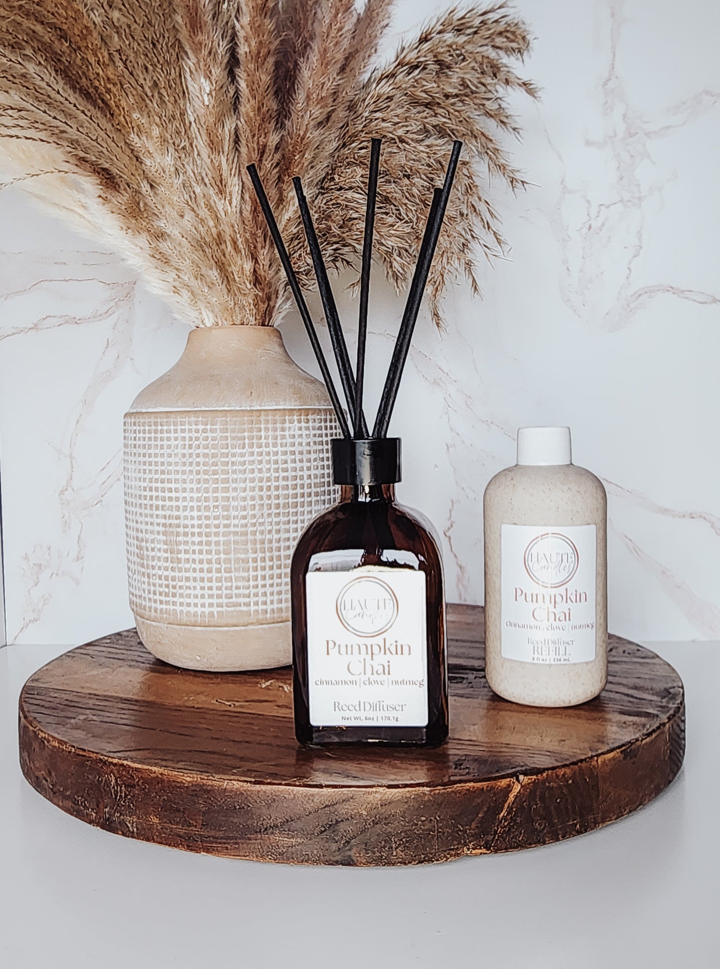 Decorative items including a diffuser, vase, and bottle on a wooden surface with a marble background.