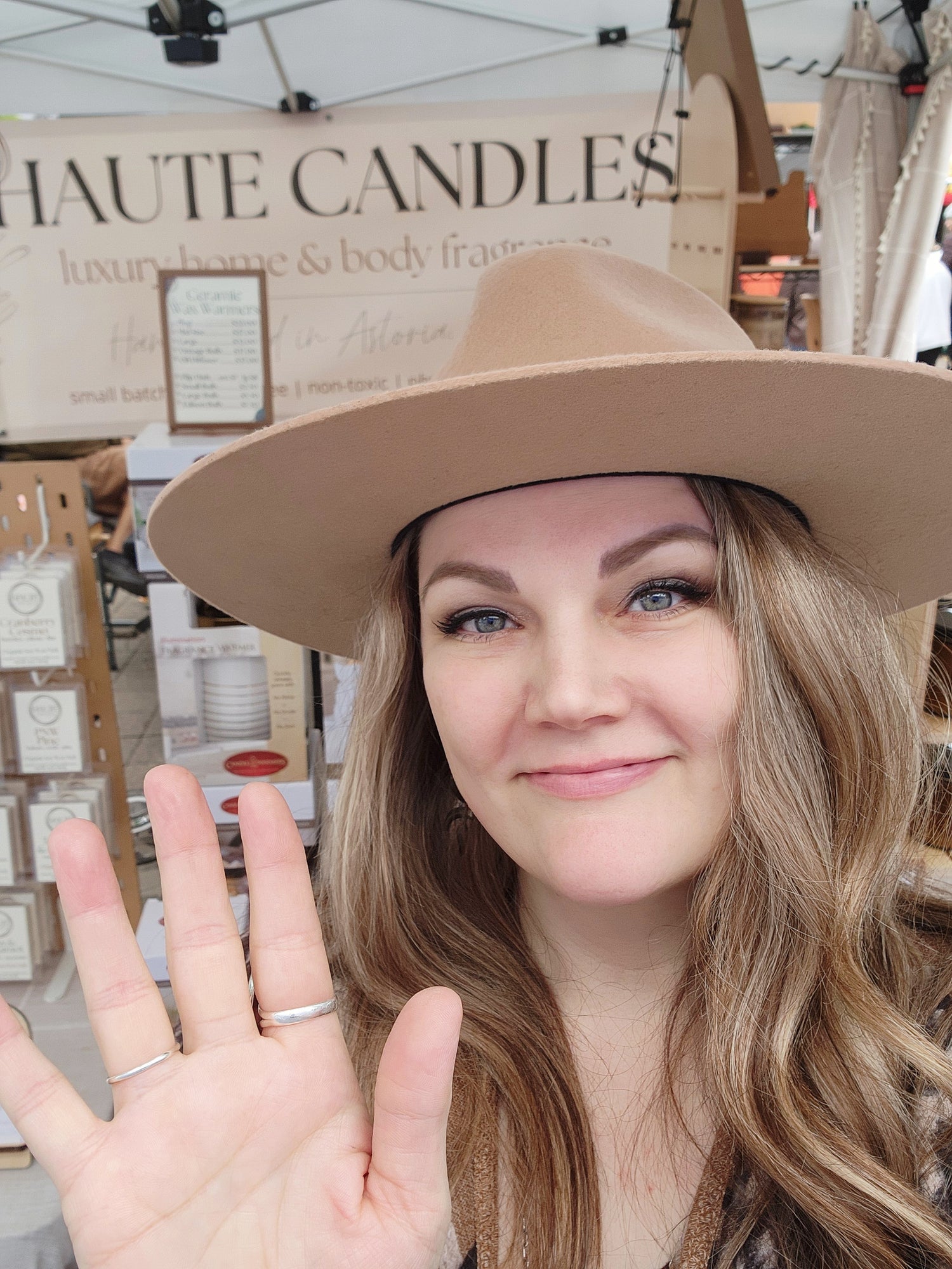Kari, founder and candle maker behind Haute Candles, waves from her market booth.